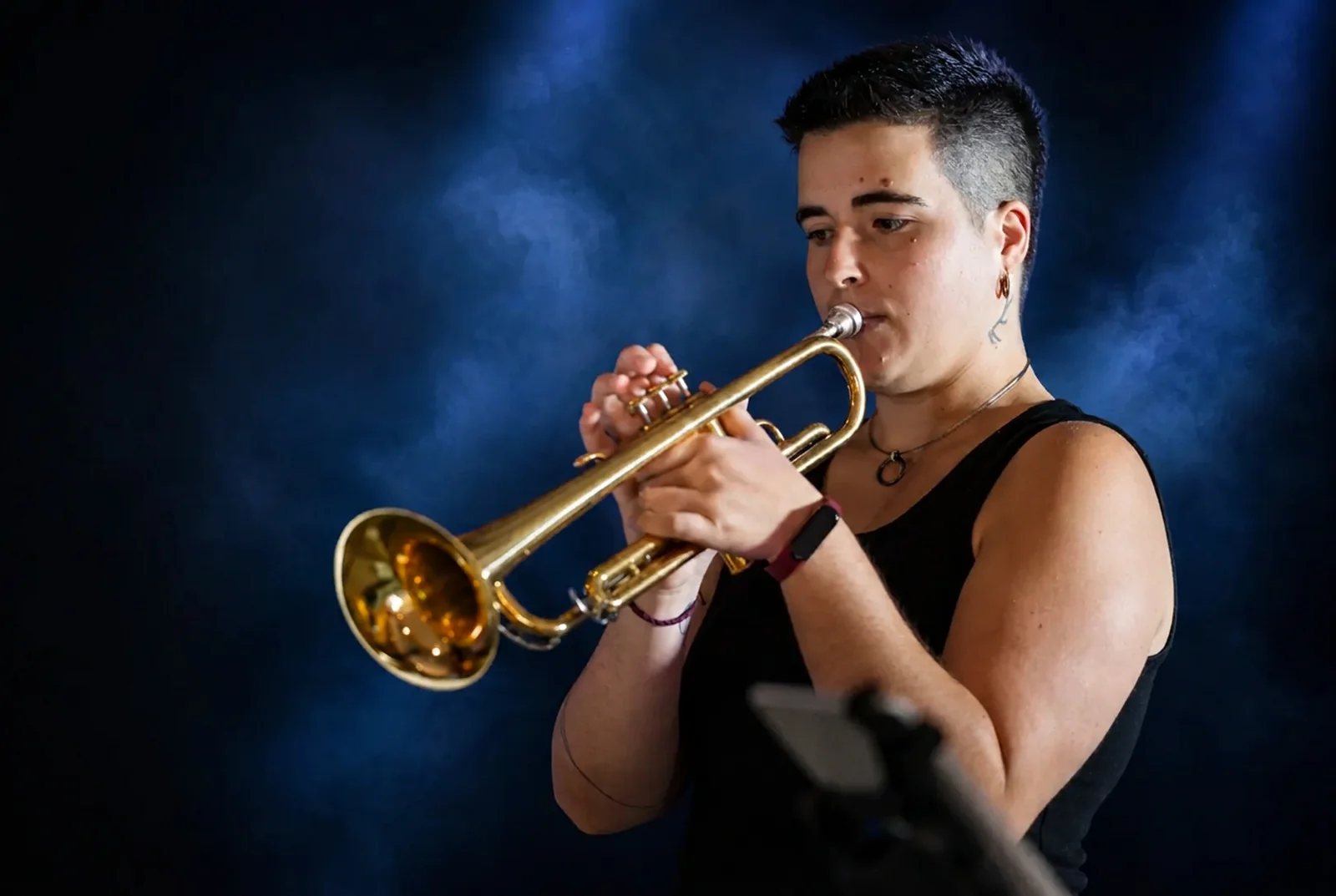 Trumpet player performing on stage under blue spotlight