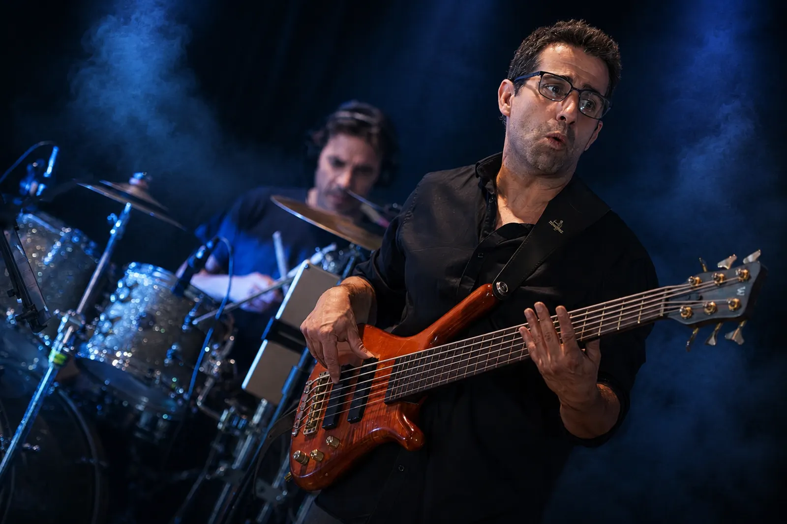 Bass guitarist playing on stage under blue stage light