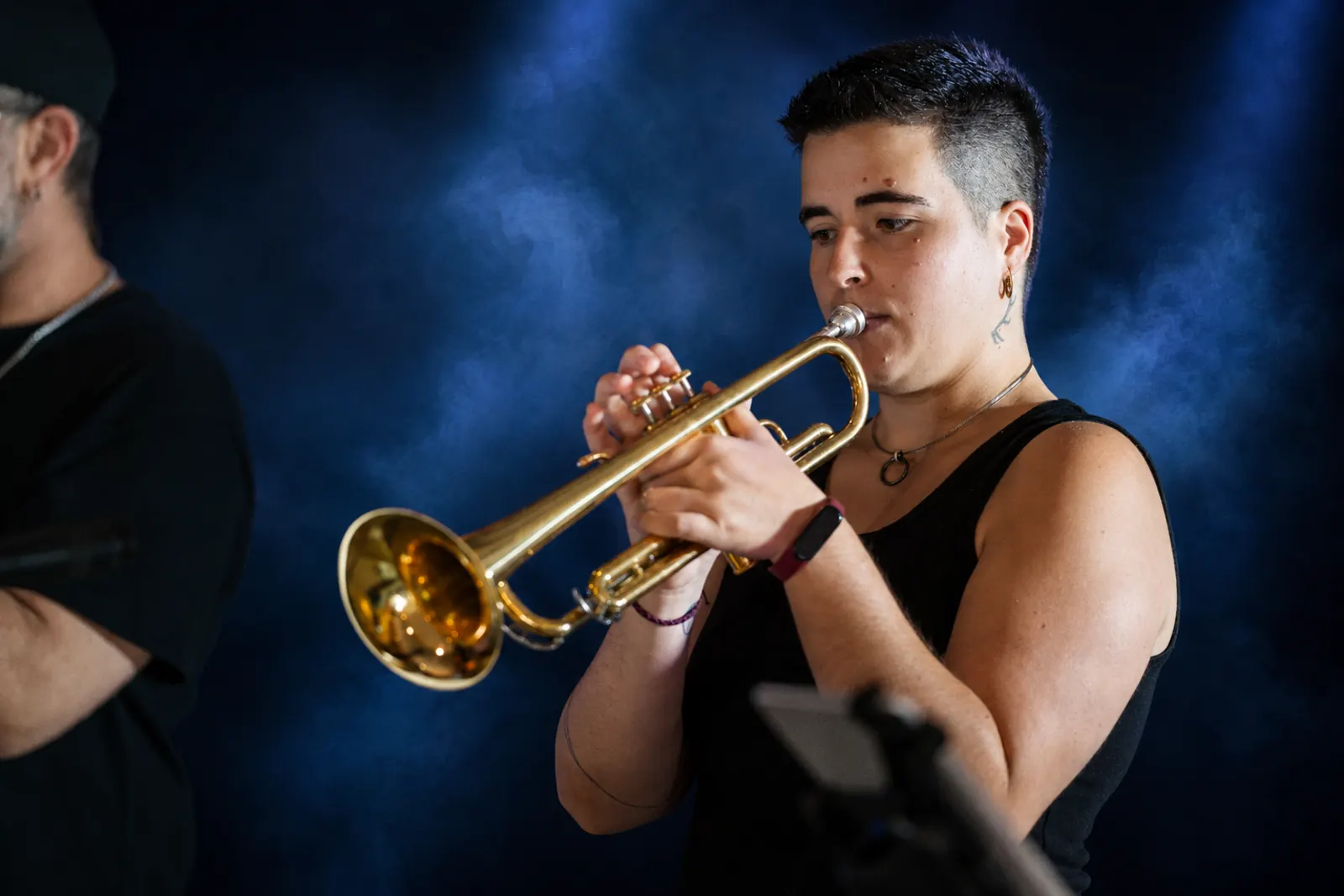 Trumpet player performing on stage under blue spotlight