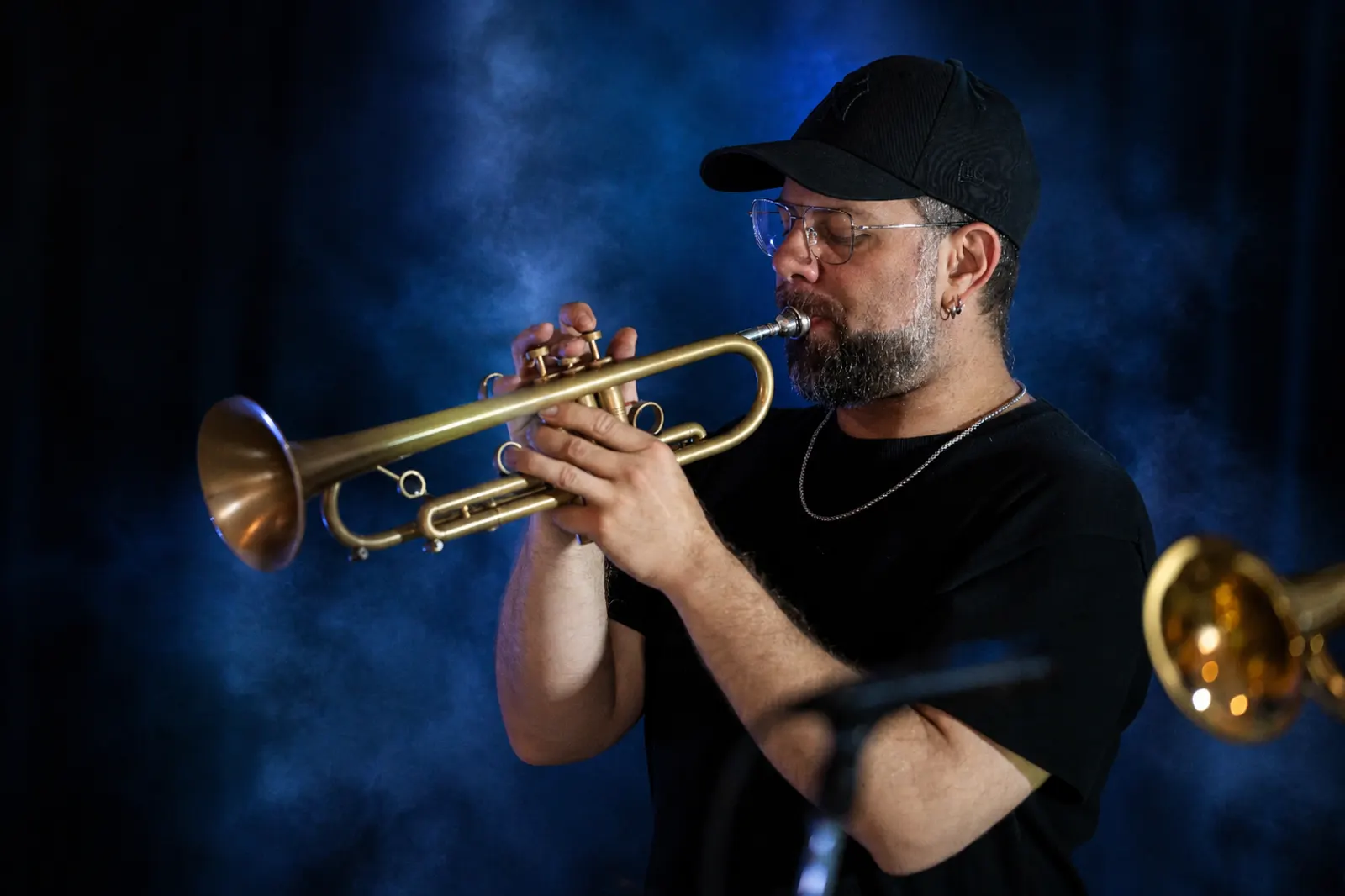 Trumpet player performing on stage with blue stage lighting